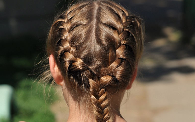 Die Haare werden dafür in der Mitte abgeteilt und an den Seiten sowie am Oberkopf in je eine Strähne geteilt.  ( Foto: Shutterstock-Nataliya Kuznetsova )